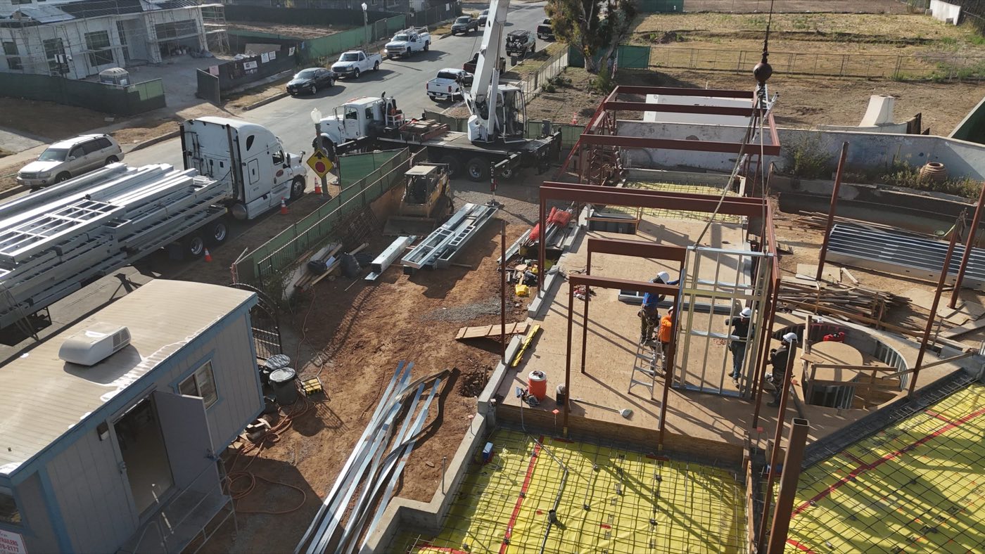 Aerial of the Palisades steel frame rising with a steel delivery on the street
